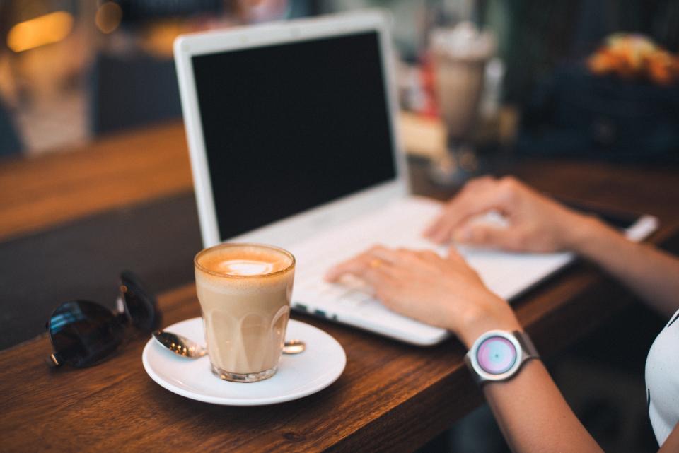 Hands on a laptop next to a latte
