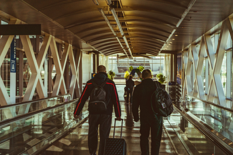 Two people walking through an airport walkway